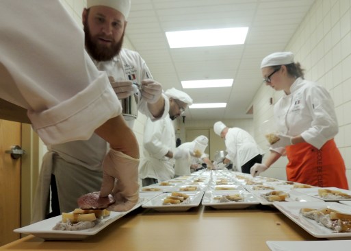 Bryce Verfaillie, at left, plates food at A Reason to Taste: City of Lights. Verfaillie and other students converted a hallway in the Student Life Center into their prep area for the multi-course fundraising dinner.