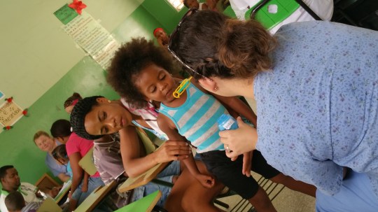 Ivy Tech Northeast nursing student Cordelia Turpchinoff applies her child development skills to entertain a young girl as she and her mother await their turn to be seen by a doctor in San Janoa de Azua.