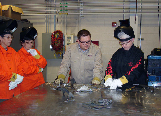 Ivy Tech associate professor, Sheri Dunlavy receives instruction before making her first weld.